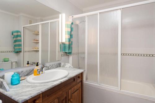 a white bathroom with a sink and a shower at La Casa del Far in Alcanada