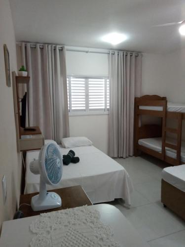 um quarto com duas camas e uma ventoinha em Kitnet à 300 metros da Canção Nova em Cachoeira Paulista