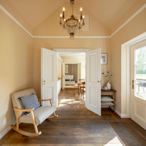 a hallway with a chair and a chandelier at Schloss Hertefeld & Hertefeldhof in Weeze