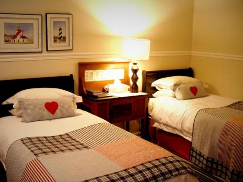 a hotel room with two beds and a table with a lamp at The Lighthouse Guesthouse in Colesberg