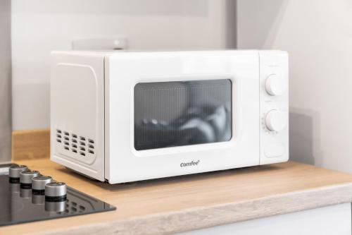 a white microwave oven sitting on top of a counter at 2 Bedroom Apartment - Private Parking - Wifi - Netflix - Top Rated - 51C in Sleightholme