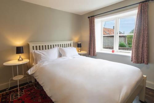a bedroom with a large white bed and a window at The Harnser in Cley next the Sea