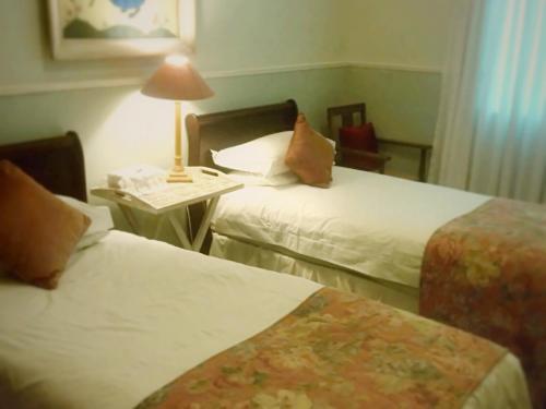 a hotel room with two beds and a table with a lamp at The Lighthouse Guesthouse in Colesberg