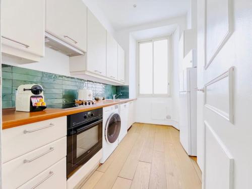 une cuisine avec des armoires blanches et une laveuse et une sécheuse dans l'établissement Le Bel Époque - Logement Centre Cannes, à Cannes