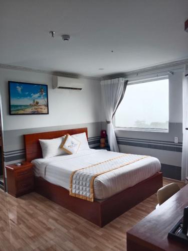 a bedroom with a bed and a large window at Rockmila Hotel in Phu Quoc
