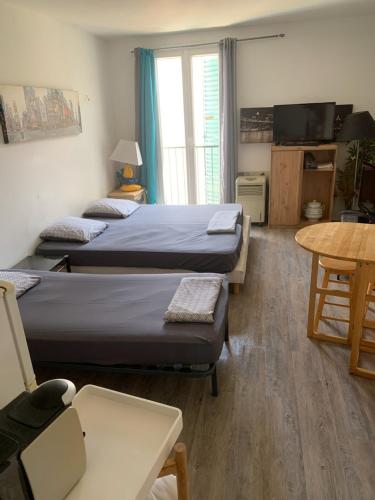 Cette chambre comprend 2 lits, une table et une télévision. dans l'établissement AJACCIO VIELLE VILLE IMPERIALE GRAND STUDIO POUR 3 a 4 PERSONNES a PROXIMITE DU PORT ET DES PLUS BELLES PLAGES, à Ajaccio