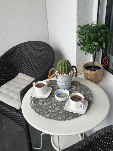 a white table with two cups of coffee and a cactus at Lux apartment 13 center, free parking in Niš