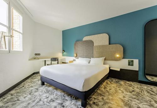 B&B HOTEL Arras Centre Les Places في أراس: غرفة نوم بسرير كبير وجدار ازرق