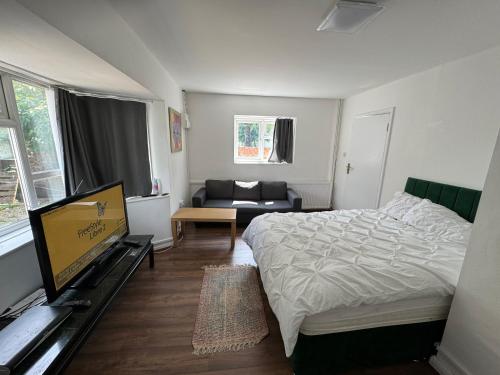 une chambre avec un lit, une télévision et un canapé dans l'établissement Renfrew Road, à Hounslow