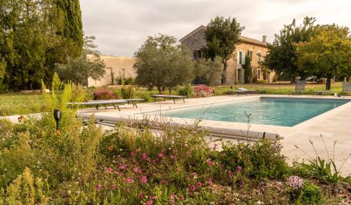 une piscine dans un jardin avec des bancs et des fleurs dans l'établissement Mas Chamsomat, à Robion