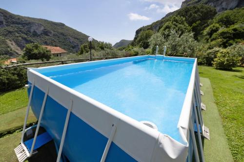 a large blue swimming pool with mountains in the background at Casa Virginia - Corbezzolo in Orco Feglino