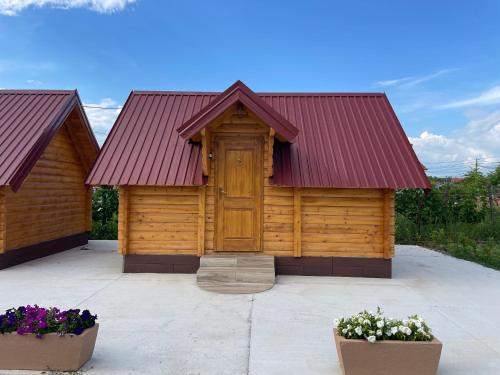 a wooden building with a red roof and two pots of flowers at Cozy bungallows in Podgorica