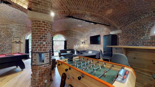 a brick room with a foosball table in the middle at Écuries Val de Mai 35 pers 5 Gîtes 15 min Amiens in Talmas