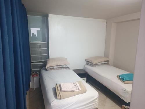 two beds in a small room with blue curtains at Assel Pousada Botanico in Curitiba
