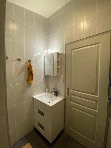 une salle de bain blanche avec un lavabo et un miroir dans l'établissement maison de lachanau, à Hourtin