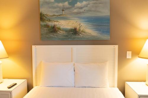 a bedroom with a bed and a painting of a beach at Sea Watch Inn at the Landing in Myrtle Beach