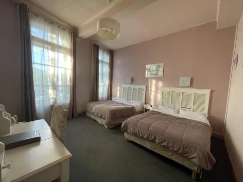 a bedroom with two beds and a desk and window at Hotel De France in Perpignan