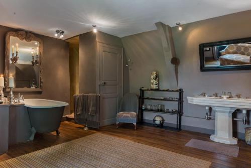 a bathroom with a tub and a sink and a mirror at Château de Saint Paterne in Saint-Paterne