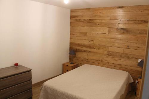 une chambre avec un lit et un mur en bois dans l'établissement Location Les Aydons, à Sainte-Marguerite-Lafigère
