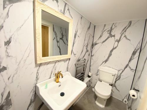 a bathroom with a sink and a toilet and a mirror at Kaoglen-GrandSuite-Hot Tub-Pitlochry-Dunkeld-Pet Friendly in Balnald