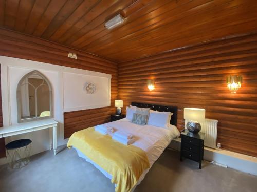um quarto com uma cama grande e paredes de madeira em Kaoglen-GrandSuite-Hot Tub-Pitlochry-Dunkeld-Pet Friendly em Balnald