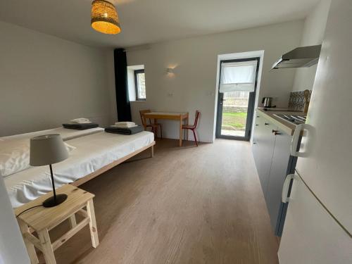 a room with a bed and a kitchen with a table at Les Pingouins du Puits in Guissény