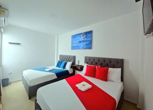 a bedroom with two beds with red and blue pillows at ANAJIRAWAA HOTEL in Ríohacha