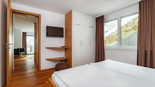 1 dormitorio con 1 cama, TV y ventana en Chalet Luna, en Zermatt