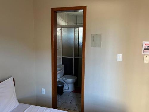 uma casa de banho com WC e uma porta que leva a um quarto em Pousada o Pelicano Ingleses em Florianópolis