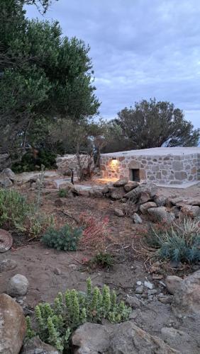 a stone building with a fireplace in a garden at Nisyros Nest in Nikiá