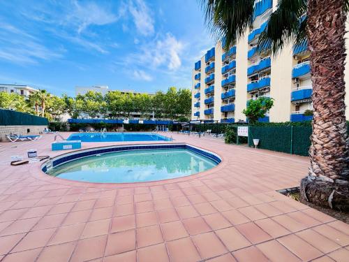 a swimming pool with a palm tree and a building at COSTA DAURADA APARTAMENTS - Alboran II in Salou