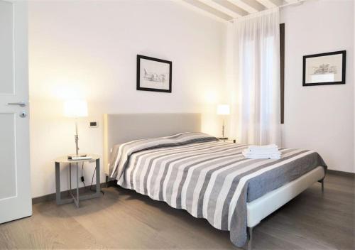 a white bedroom with a bed and a window at Stylish apartment 100 meters from San Marco square in Venice