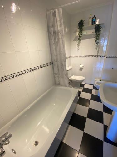 a bathroom with a white tub and a black and white checkered floor at Avenida 37 in Caldas de Reis