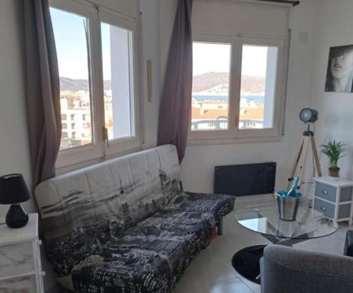 a living room with a couch and a table and windows at Appartement port Nautic 5 Empuria in Empuriabrava