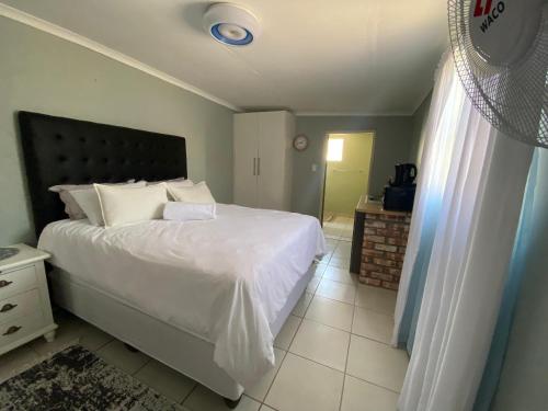 a bedroom with a white bed with a black headboard at Inecia's B & B in Uis