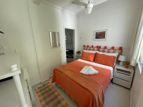 um quarto com uma cama com lençóis laranja em Apartamento Maré Mansa a 30 metros da praia Mansa em Caiobá com Wifi em Caiobá