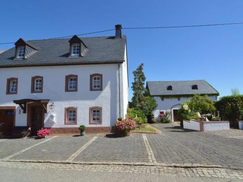a large white house with a cobblestone driveway at Appealing Apartment in Ittel with Garden Parking Bicycles in Welschbillig