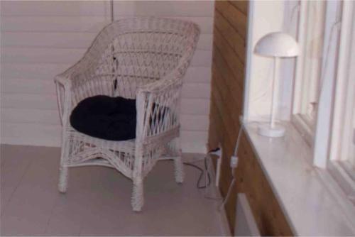 a wicker chair with a black cushion in a room at Loberget Oviken in Oviken