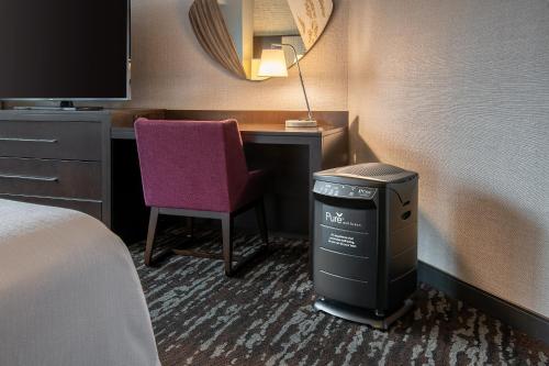 a hotel room with a desk with a trash can and a chair at Embassy Suites by Hilton Crystal City National Airport in Arlington