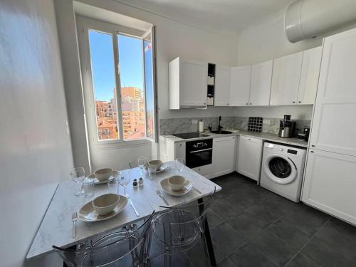 une cuisine blanche avec une table et des chaises dans l'établissement Centre Ville, près de Casino et gare de Monaco, à Beausoleil