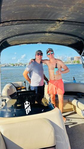two men standing in the back of a boat at SunBoat Rental - Pontoon Boat Rental in Dania Beach