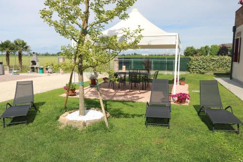 a group of chairs and a tree with a tent at Casa al Piave - appartamento a 5 km dal mare in Eraclea