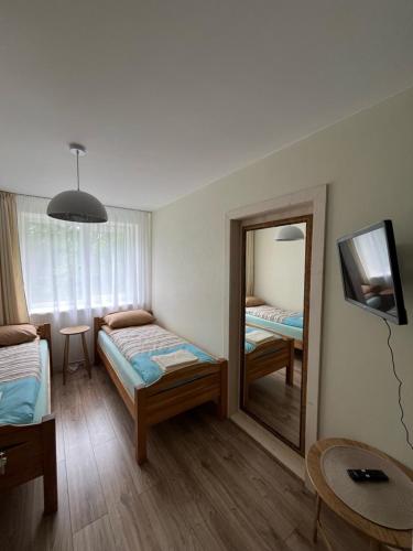 a small room with two beds and a mirror at Jaukaus buto nuoma Šiaulių rajone in Šapnagiai
