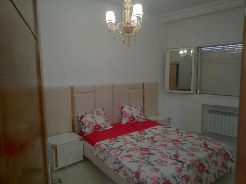 1 dormitorio con 1 cama con manta roja y lámpara de araña en Residence Amira, en Monastir