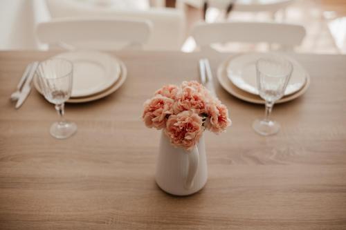 a white vase filled with pink flowers on a table at Studio cocoon hypercentre Carré d'or de Strasbourg in Strasbourg