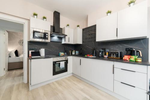 a white kitchen with white cabinets and appliances at Ty Ayla Premier Apartments - Roath Park in Cardiff