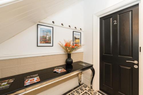 a staircase with a black door and a vase on a table at Ty Ayla Premier Apartments - Roath Park in Cardiff