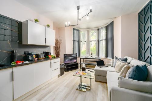 a living room with a couch and a kitchen at Ty Ayla Premier Apartments - Roath Park in Cardiff
