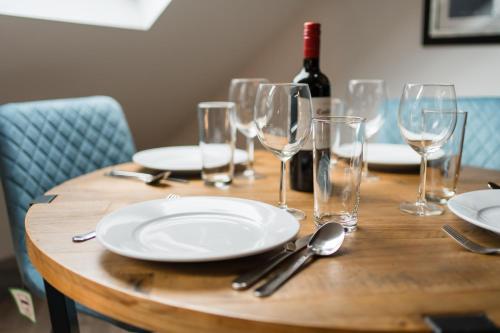 a wooden table with empty glasses and a bottle of wine at Ty Ayla Premier Apartments - Roath Park in Cardiff