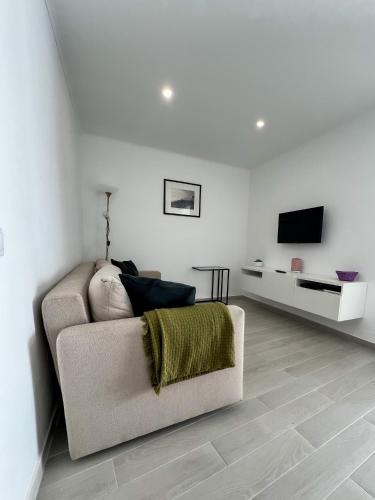 a white living room with a couch and a tv at Casa Dos Borrachos in Aldeia do Mato